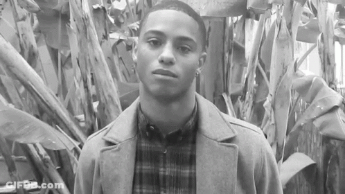 Young Man In Coat And Plaid Shirt By Tree GIF