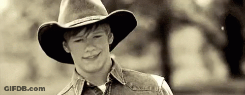 Young Man In Cowboy Hat And Denim Vest Smiling GIF
