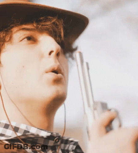 Young Man In Cowboy Hat And Plaid Shirt Holding Gun GIF