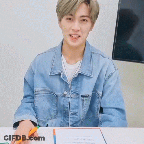 Young Man In Denim Jacket Sitting At Table GIF