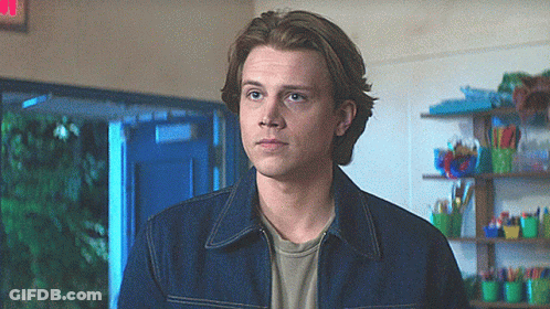 Young Man In Denim Jacket With Red Exit Sign GIF