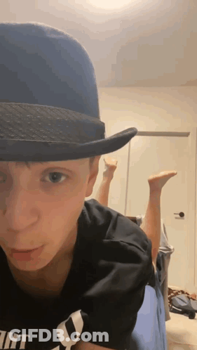 Young Man In Fedora Lying On Bed GIF