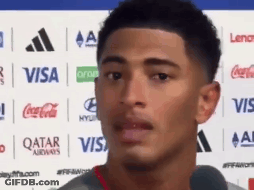 Young Man In Front Of Visa Coca Cola Qatar Airways Logos GIF