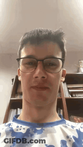 Young Man In Glasses And Camo Shirt Looking At Camera GIF