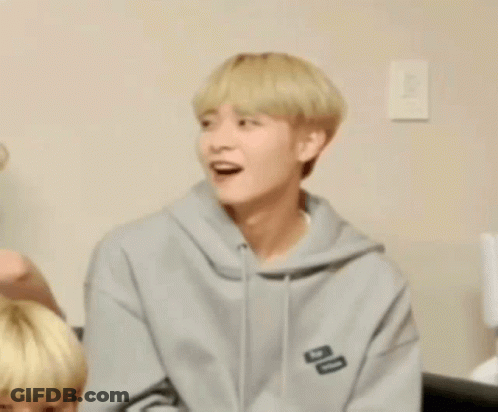Young Man In Gray Hoodie Sitting On Couch GIF