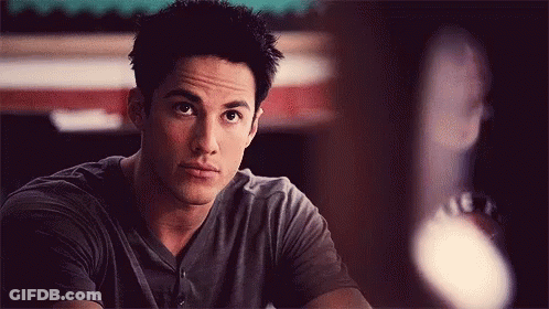 Young Man In Gray Shirt Sitting At Table GIF
