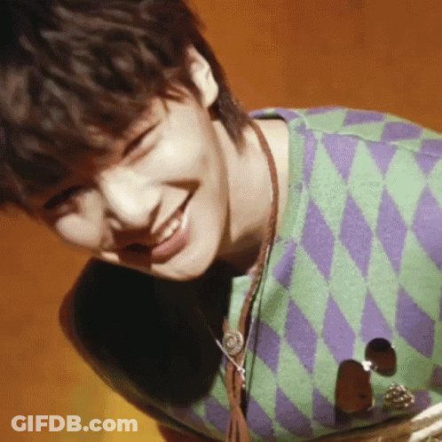 Young Man In Green And Purple Sweater Smiles GIF