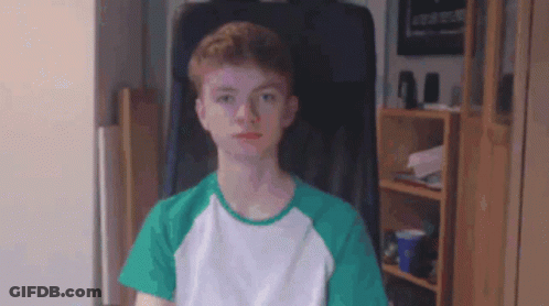 Young Man In Green And White Shirt Sitting In Chair GIF