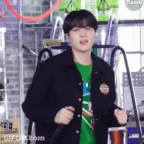 Young Man In Green Shirt And Black Jacket Standing At Microphone GIF