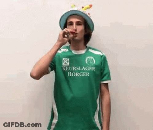 Young Man In Green Shirt Blowing Party Horn GIF