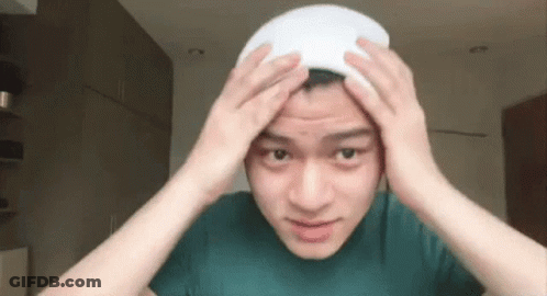Young Man In Green Shirt Holding White Towel On Head GIF