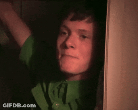 Young Man In Green Shirt Looking Out Doorway GIF