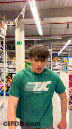 Young Man In Green T-Shirt Standing In Store GIF