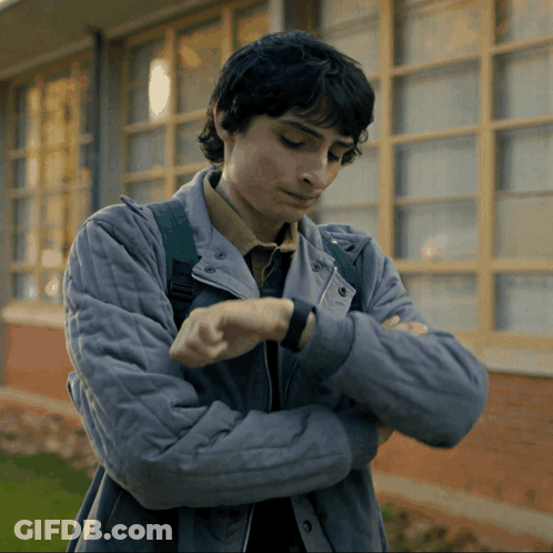 Young Man In Grey Jacket Looking At Watch GIF