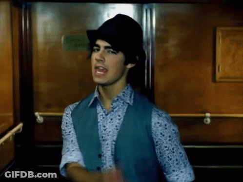 Young Man In Hat And Vest Standing In Elevator GIF