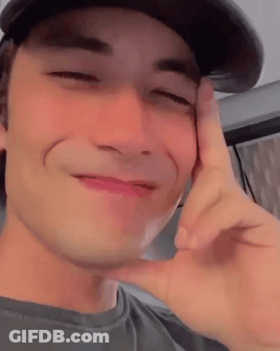 Young Man In Hat Making Funny Face With Hand On Face GIF