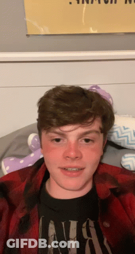 Young Man In Nirvana Shirt Laying On Bed GIF