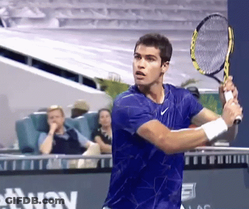 Young Man In Orange Shirt Swinging Tennis Racquet GIF