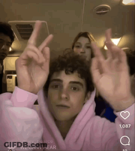 Young Man In Pink Hoodie Giving Peace Sign GIF
