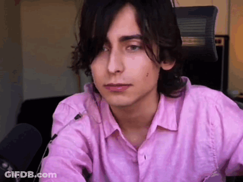 Young Man In Pink Shirt Sitting At Microphone GIF