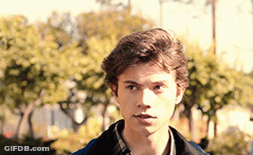 Young Man In Plaid Shirt And Blue Jacket Before Trees GIF