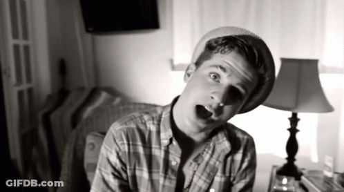 Young Man In Plaid Shirt And Hat In Front Of Lamp GIF