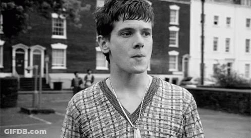 Young Man In Plaid Shirt Standing In Front Of Building GIF