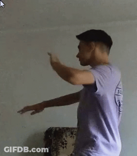 Young Man In Purple Shirt And White Shorts Standing In Front Of Couch GIF