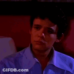 Young Man In Purple Shirt Sitting In Dark Room GIF