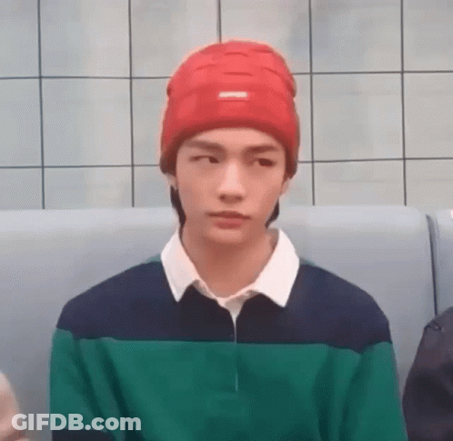 Young Man In Red Beanie And Green Blue Shirt Sitting On Couch GIF