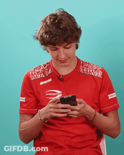 Young Man In Red Errea Shirt Looking At Phone GIF