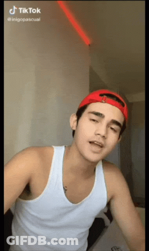Young Man In Red Hat And White Tank Top Making TikTok Video GIF