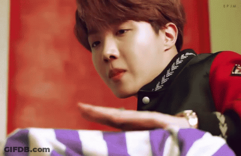 Young Man In Red Jacket Holding Purple And White Striped Blanket GIF