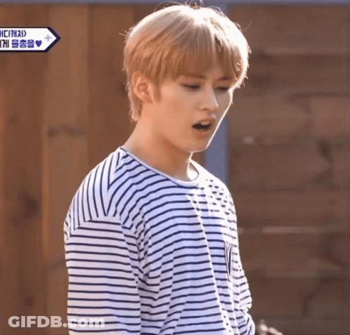 Young Man In Striped Shirt Standing Before Wooden Door GIF