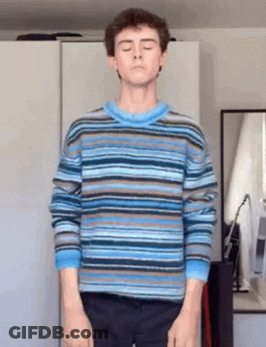 Young Man In Striped Sweater In Front Of Mirror GIF