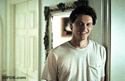 Young Man In Striped T-Shirt Smiling In Hallway GIF