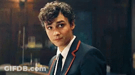 Young Man In Suit And Tie Looking At Camera In Dark Room GIF