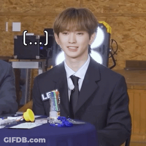 Young Man In Suit And Tie Sitting At Table GIF