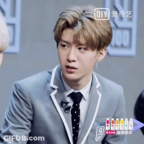 Young Man In Suit And Tie With Bottle Of Ioiyi GIF