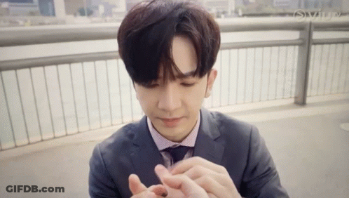 Young Man In Suit Holding Small Object GIF