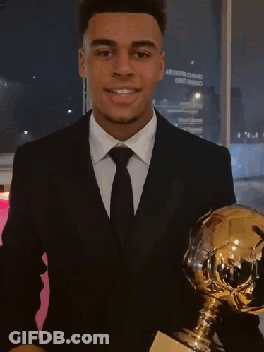 Young Man In Suit Holding Trophy GIF