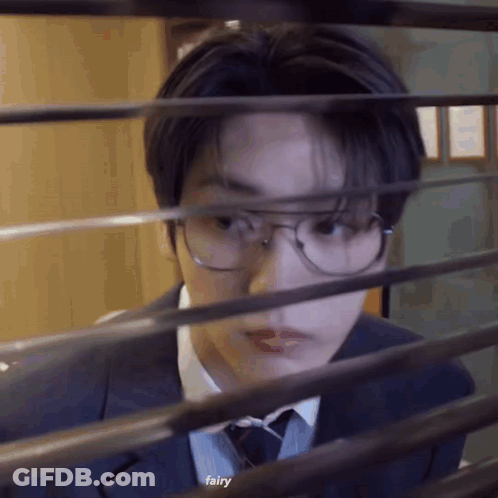 Young Man In Suit Looking Through Window GIF