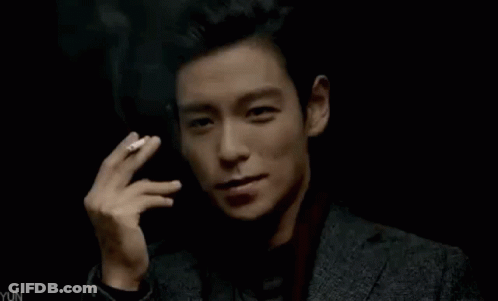 Young Man In Suit Smoking Cigarette In Dark Room GIF