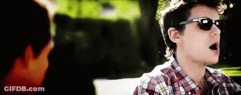 Young Man In Sunglasses And Plaid Shirt Talking To Another GIF