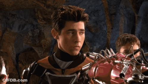 Young Man In Superhero Costume Next To Robotic Arm GIF