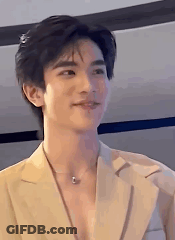 Young Man In Tan Jacket And Necklace Smiling GIF