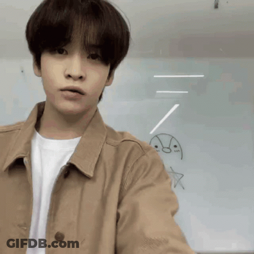 Young Man In Tan Jacket Standing Before Drawings GIF