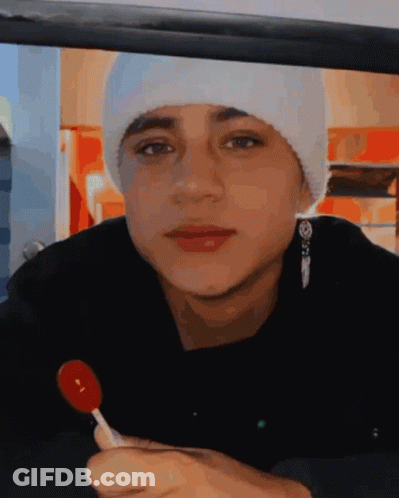 Young Man In White Beanie Holding Red Lollipop GIF