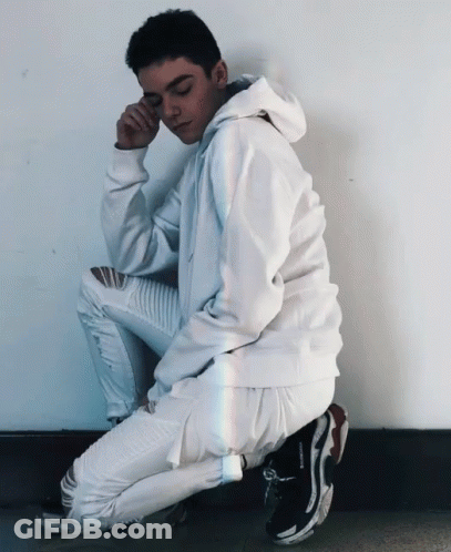 Young Man In White Hoodie And Jeans Squatting GIF