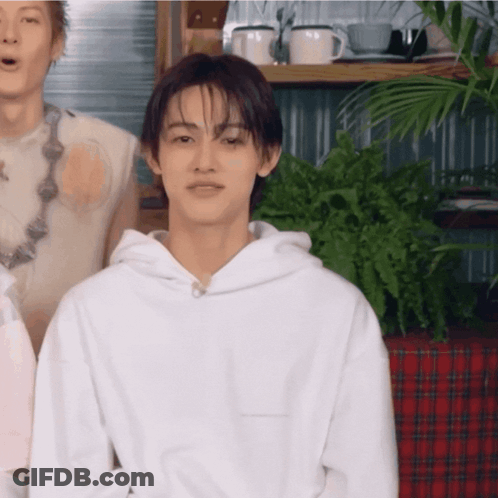 Young Man In White Hoodie By Shelf Of Mugs GIF